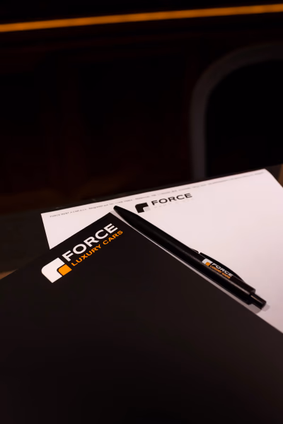 Brendirana fascikla i hemijska olovka sa logom FORCE Luxury Cars na poslovnom papiru.